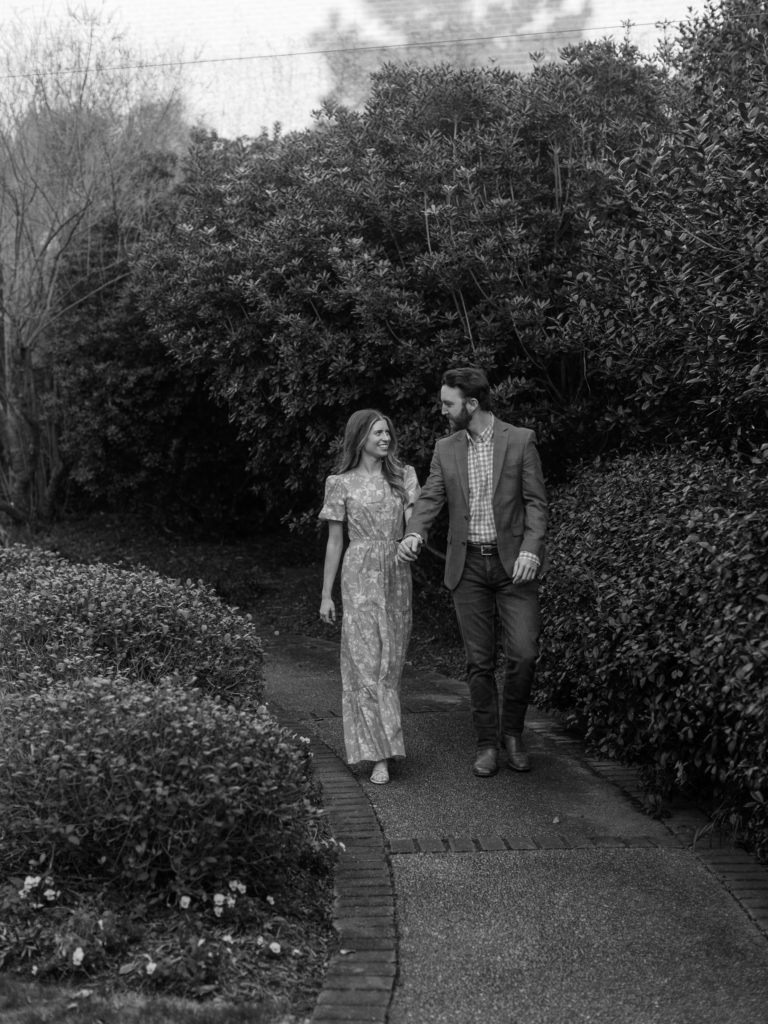 Black and white image of man and woman at the Mississippi Museum of Art wearing a french blue cut out maxi dress and a grey suit with a gingham shirt.